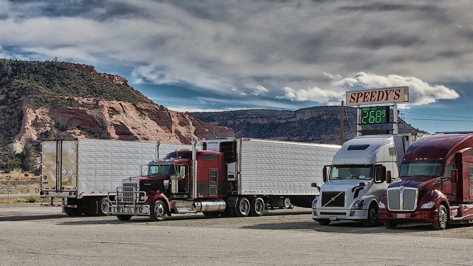 Semi Truck and Trailers at a Gas Station Entering the Mountains of New Mexico. [{'name': '66', 'accuracy': None, 'unstable__provider': 'flickr'}, {'name': 'american', 'accuracy': None, 'unstable__provider': 'flickr'}, {'name': 'big', 'accuracy': None, 'unstable__provider': 'flickr'}, {'name': 'building', 'accuracy': None, 'unstable__provider': 'flickr'}, {'name': 'business', 'accuracy': None, 'unstable__provider': 'flickr'}, {'name': 'car', 'accuracy': None, 'unstable__provider': 'flickr'}, {'name': 'cargo', 'accuracy': None, 'unstable__provider': 'flickr'}, {'name': 'chro. Ilustracija uz vest: Tesla Semi izabran kao glavni kamion za rekordnu američku porudžbinu električnih tegljača
