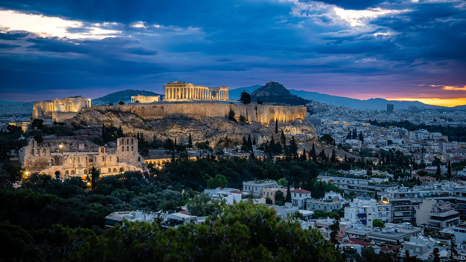 Athens Acropolis at Daybreak.jpg. The first hints of sunrise brushed the Athens skyline, molten gold pressing against the lingering blues of night. From our perch on Philopappou Hill, the Acropolis stood quietly opposite, still flood-lit from the evening. A small band of us had gathered in the hotel lobby before dawn and climbed the hill as blue hour faded. We’d been here the previous evening, taking in views all the way to the Aegean, but this time our gaze turned east toward Lycabettus Hill and the ancient structures of the Od. Ilustracija uz vest: Eksplozija kod Akropolja srušila zgradu: jedna osoba poginula, pet se vodi kao nestalo